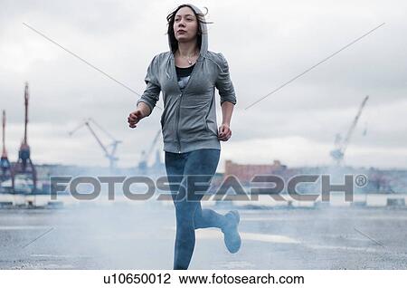 Young female runner running on stormy dockside View Large Photo Image Stock Image - Young female runner running on stormy dockside. Fotosearch