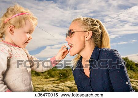 Young girl feeding mother blueberry View Large Photo Image Stock Photography - Young girl feeding mother blueberry. Fotosearch