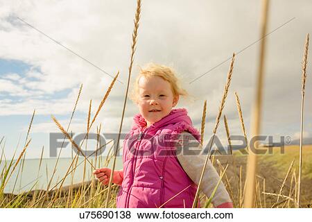 Young girl in field, holding ear of wheat View Large Photo Image Stock Photo - Young girl in field, holding ear of wheat. Fotosearch