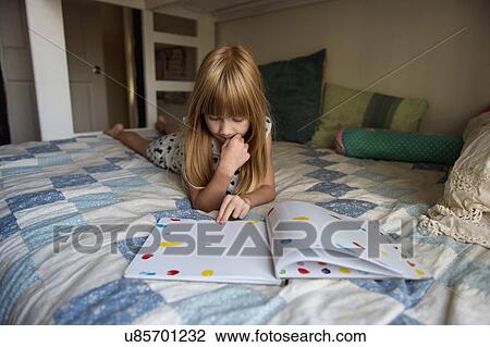 Young girl laying on bed reading book View Large Photo Image Stock Image - Young girl laying on bed reading book. Fotosearch