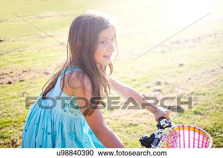 Stock Image - Young girl riding bike in summer. Fotosearch