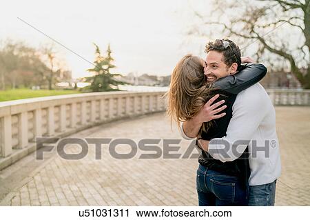 Stock Image - Young happy couple hugging in Battersea Park, London, UK. Fotosearch