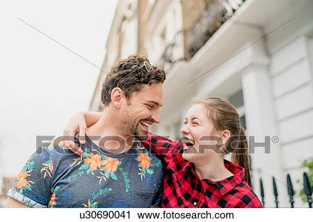 Stock Image - Young happy couple strolling along street, Kings Road, London, UK. Fotosearch