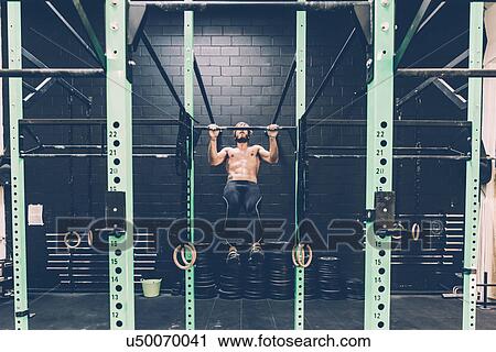 Young male cross trainer doing chin ups on exercise bar in gym View Large Photo Image Stock Image - Young male cross trainer doing chin ups on exercise bar in gym. Fotosearch