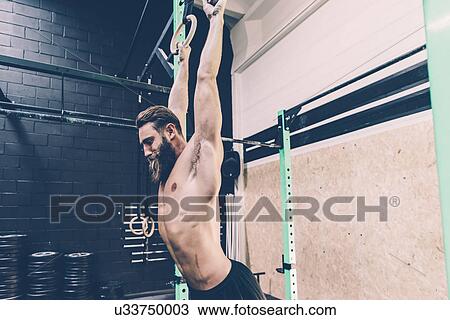 Young male cross trainer hanging from exercise rings in gym View Large Photo Image Stock Image - Young male cross trainer hanging from exercise rings in gym. Fotosearch