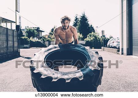Young male cross trainer lifting heavy tyre outside gym View Large Photo Image Picture - Young male cross trainer lifting heavy tyre outside gym. Fotosearch
