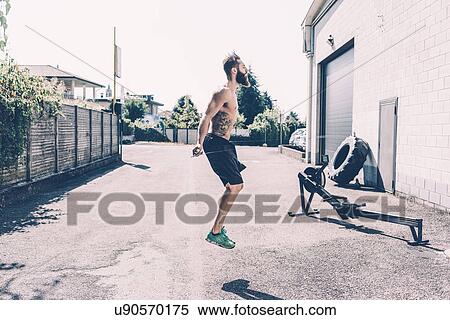 Stock Photography - Young male cross trainer skipping outside gym. Fotosearch