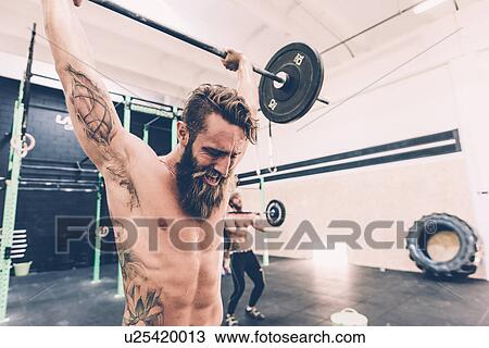 Young male cross trainer snatch lifting barbell in gym View Large Photo Image Stock Image - Young male cross trainer snatch lifting barbell in gym. Fotosearch