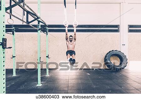 Stock Image - Young male cross trainer training on gymnastic rings. Fotosearch