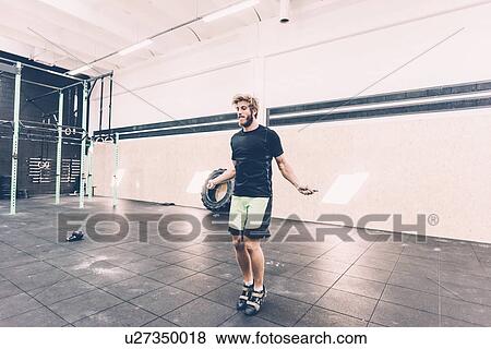 Young male cross trainer training with skipping rope in gym View Large Photo Image Stock Photo - Young male cross trainer training with skipping rope in gym. Fotosearch