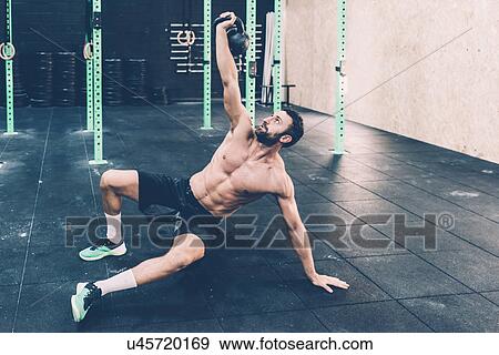 Young male cross trainer training with kettlebell in gym View Large Photo Image Stock Photo - Young male cross trainer training with kettlebell in gym. Fotosearch