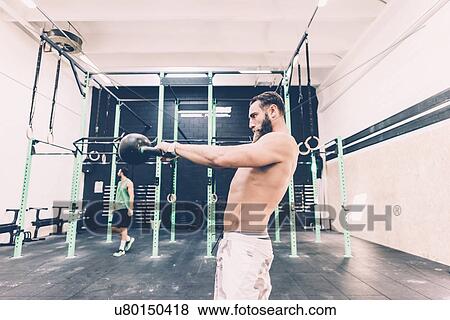 Young male cross trainer weightlifting kettlebell in gym View Large Photo Image Stock Photo - Young male cross trainer weightlifting kettlebell in gym. Fotosearch