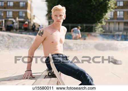 Young male skateboarder looking over his shoulder in skatepark View Large Photo Image Stock Image - Young male skateboarder looking over his shoulder in skatepark. Fotosearch