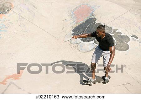 Young male skateboarder skateboarding in skatepark View Large Photo Image Stock Image - Young male skateboarder skateboarding in skatepark. Fotosearch