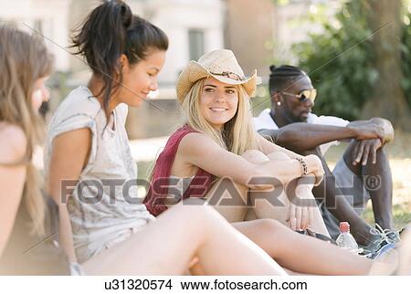 Young man and female friends chatting in park View Large Photo Image Picture - Young man and female friends chatting in park. Fotosearch