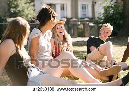 Young man and female friends chatting in park View Large Photo Image Stock Photo - Young man and female friends chatting in park. Fotosearch