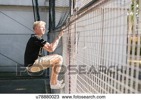 Young man climbing wire fence View Large Photo Image Stock Image - Young man climbing wire fence. Fotosearch