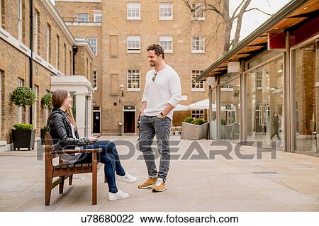 Young man greeting girlfriend sitting on bench, Kings Road, London, UK View Large Photo Image Stock Image - Young man greeting girlfriend sitting on bench, Kings Road, London, UK. Fotosearch