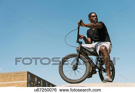Stock Photograph - Young man on BMX bicycle looking over his shoulder in skatepark. Fotosearch