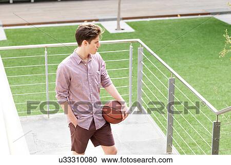 Young man outdoors, holding basketball View Large Photo Image Stock Image - Young man outdoors, holding basketball. Fotosearch