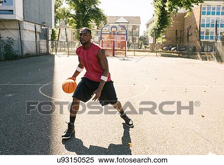Stock Photography - Young man practising on basketball court. Fotosearch