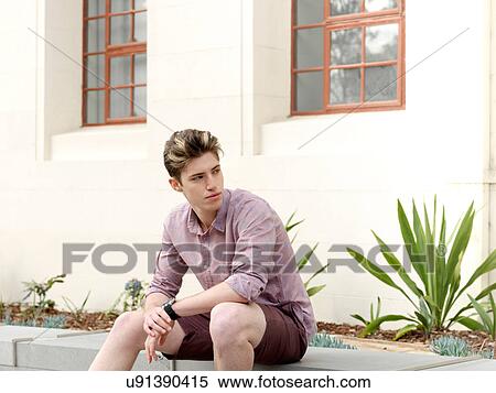 Young man sitting on step, outdoors, looking away View Large Photo Image Stock Photography - Young man sitting on step, outdoors, looking away. Fotosearch