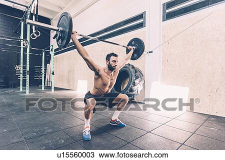 Young man weightlifting barbell in cross training gym View Large Photo Image Stock Image - Young man weightlifting barbell in cross training gym. Fotosearch