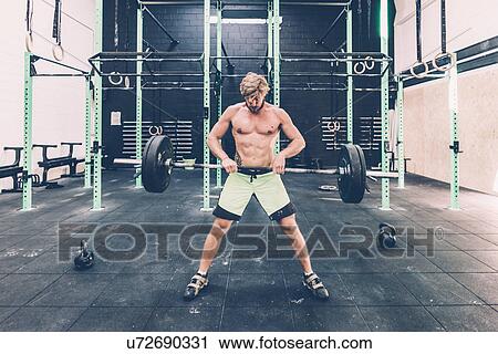 Young man weightlifting barbell in cross training gym View Large Photo Image Stock Image - Young man weightlifting barbell in cross training gym. Fotosearch