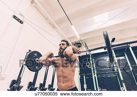 Young man weightlifting barbell in cross training gym View Large Photo Image Stock Photography - Young man weightlifting barbell in cross training gym. Fotosearch