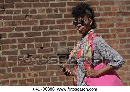 Stock Photograph - Young woman against brick wall. Fotosearch