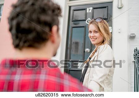 Stock Photography - Young woman and boyfriend at front door, Kings Road, London, UK. Fotosearch