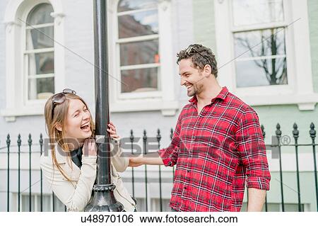 Stock Photograph - Young woman and boyfriend fooling around on street, Kings Road, London, UK. Fotosearch
