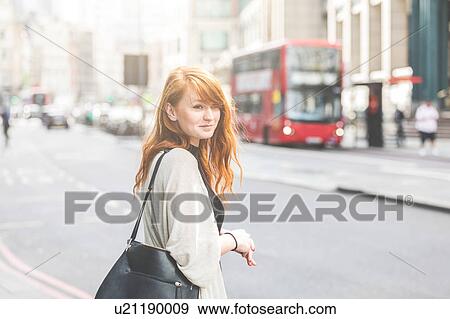 Stock Photo - Young woman crossing street, London, UK. Fotosearch