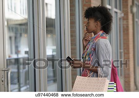 Young woman looking at store window View Large Photo Image Stock Photo - Young woman looking at store window. Fotosearch