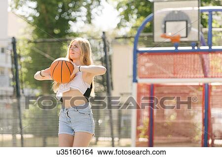 Picture - Young woman practising on basketball court. Fotosearch