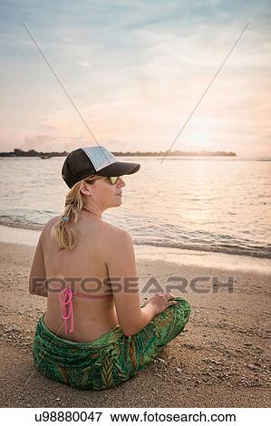 Young woman sitting cross legged on beach, Gili Meno, Lombok, Indonesia View Large Photo Image Stock Photo - Young woman sitting cross legged on beach, Gili Meno, Lombok, Indonesia. Fotosearch