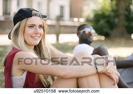 Stock Photo - Young woman sitting in park. Fotosearch