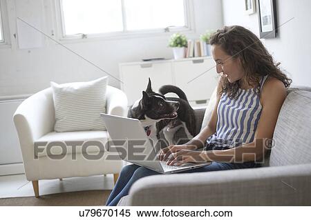 Young woman sitting on sofa with laptop and dog View Large Photo Image Stock Photography - Young woman sitting on sofa with laptop and dog. Fotosearch