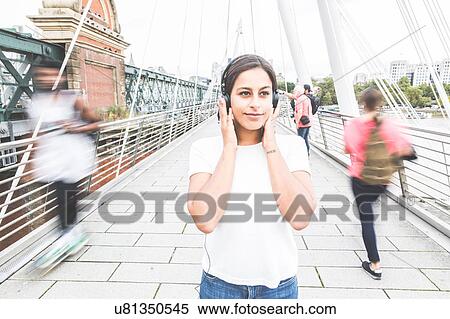 Young woman standing on bridge, wearing headphones View Large Photo Image Stock Photography - Young woman standing on bridge, wearing headphones. Fotosearch