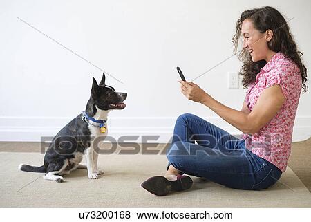 Stock Photo - Young woman taking photograph of her dog. Fotosearch