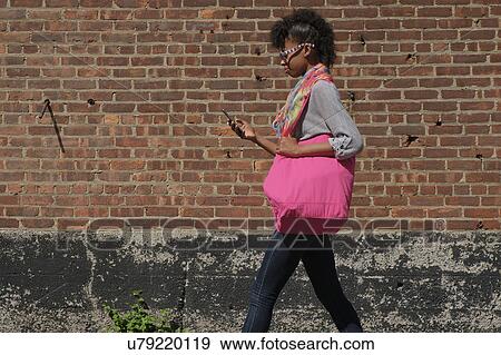 Young woman walking against brick wall View Large Photo Image Stock Photo - Young woman walking against brick wall. Fotosearch