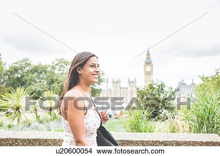 Picture - Young woman walking outdoors, Houses of parliament and Big Ben in background, London, England. Fotosearch