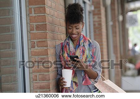 Young woman with shopping bags leaning against brick wall View Large Photo Image Stock Photograph - Young woman with shopping bags leaning against brick wall. Fotosearch