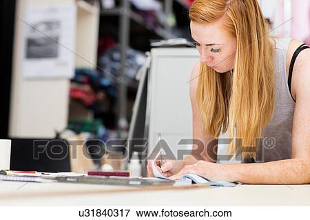 Stock Photo - Young woman working in leather jacket manufacturers, close-up. Fotosearch