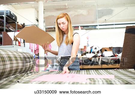 Stock Photo - Young woman working in leather jacket manufacturers. Fotosearch