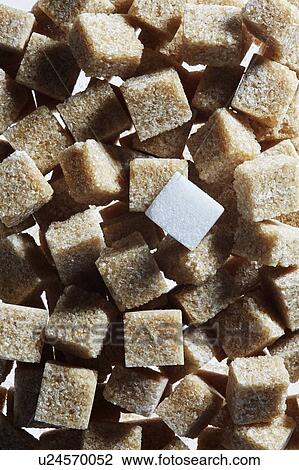 Stock Image - Brown sugar cubes with single white sugar cube. Fotosearch
