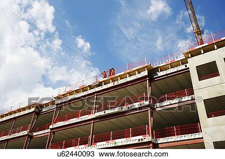 Stock Image - Construction workers on top of building. Fotosearch