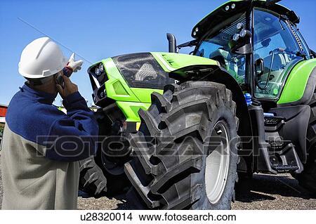 Picture - Farmer on the phone pointing at tractor. Fotosearch