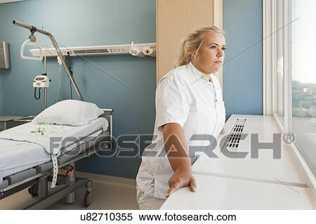 Stock Photography - Female nurse looking out of window. Fotosearch