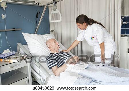 Stock Image - Female nurse with hand on patient's shoulder. Fotosearch